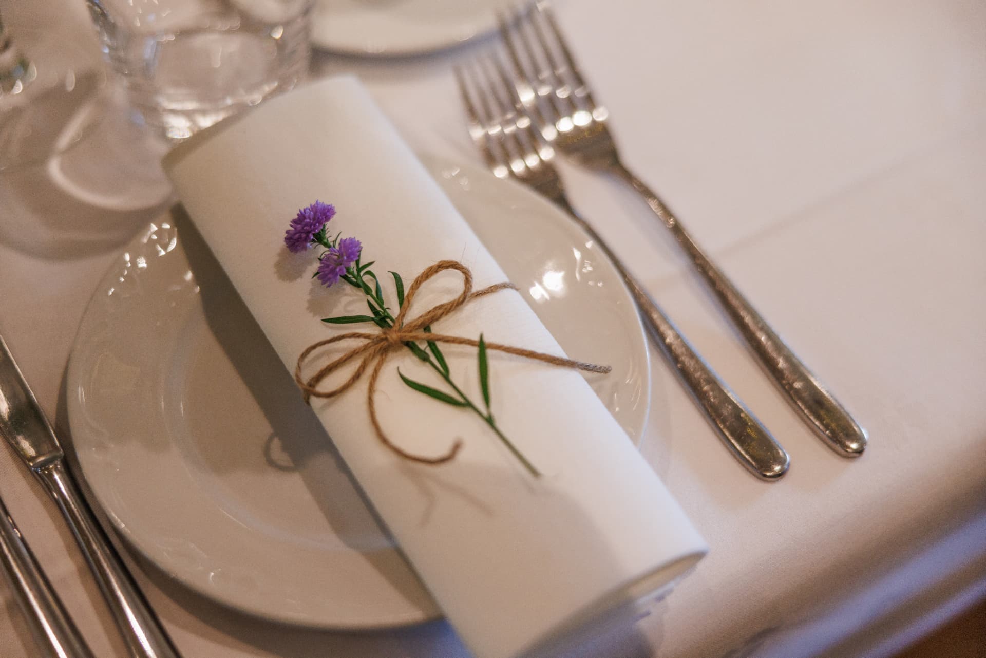 Serviett med blomst og tvinn på dekket bord